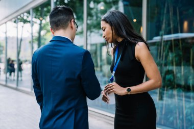 Modern Afrikalı zarif kadın ve kimliği olan erkek şehir caddesinde yan yana durur ve boş vakitlerinde sohbet ederken cep telefonu kullanırlar. 