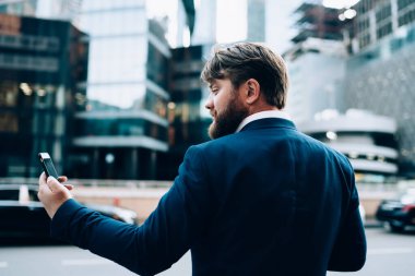 Şaşkın iş adamının cep telefonu aygıtıyla cep telefonundan gelen mesajları kontrol edişinin arka görüntüsü, profesyonel para web sitesinde haber okuyan Kafkas erkek finans uzmanı