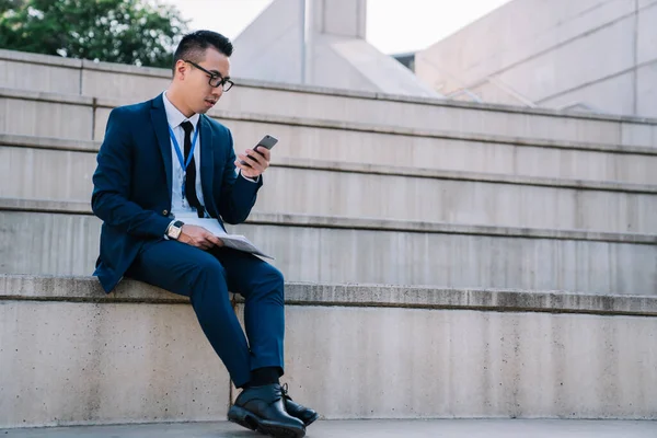 Elegante Hombre Asiático Con Traje Gafas Sentados Valla Hormigón Celebración —  Fotos de Stock