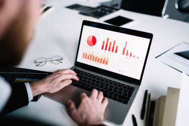 Şirketin mali tabloları üzerinde çalışırken masa başında oturan ve dizüstü bilgisayar kullanan iş adamlarından. 