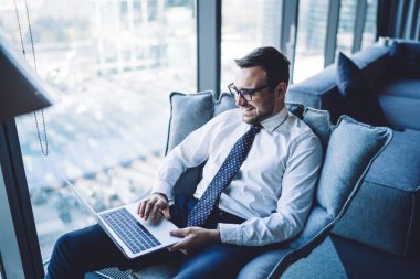 Resmi giyinmiş pozitif erkek patron iş gezisi sırasında arkadaşları ve ailesiyle video konferansında eğleniyor. Gözlük okuyan mutlu adam ofisinde otururken bilgisayardan e-posta alıyor.