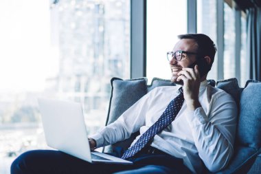 Gözlüklü mutlu bir adamın bakışları başka tarafa bakıyor ve akıllı telefon cihazıyla arkadaşlarıyla iletişim kurarken gülümsüyor. Ofiste dizüstü bilgisayarla oturuyor, iş dünyası liderleri kavramını kullanıyor.
