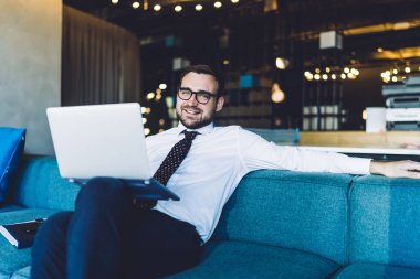 Finansal fikirler üretmek için zaman harcayan mutlu iş adamının portresi dizüstü bilgisayarla oturan başarılı profesyonel girişimci beyaz gömlek ve kravat giyen taşınabilir netbook kullanıyor.