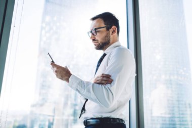 İçerideki 4G bağlantısını kullanarak SMS mesajlarını kontrol eden konsantre bir adamın yan görüntüsü, modern cep telefonunda arama yapan gözlüklü beyaz erkek şirket müdürü.