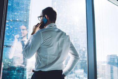 Resmi olarak giyinmiş gururlu CEO 'nun arka planı ofis içi telefonundan arıyor. Girişim şirketinde iş günü boyunca erkek girişimci müşteriyle cep telefonuyla konuşuyor.