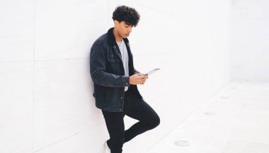 Moda giyinmiş erkek blogcu, internet sitesinde şık kıyafetler giyen ve içerik web sitesinde haber okuyan, bin yıllık Latin asıllı adam, yayın yakınlarındaki yorumları tartışan takipçilerle çevrimiçi sohbet etmek için dokunmatik sayfayı kullanıyor.