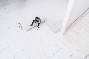 Modern şehir ortamında, internet bağlantısı ve araştırma bilgilerini dizüstü bilgisayar siteleri ve strateji hesap dökümanları, uzak iş bilgileri ile birlikte oturan yetenekli erkek serbest çalışanın havadan görünüşü