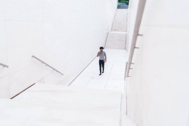 Beyaz AVM 'de elinde belgelerle dolaşırken akıllı telefondan konuşan gündelik kıyafetlerle üst düzey etnik bir adamdan.