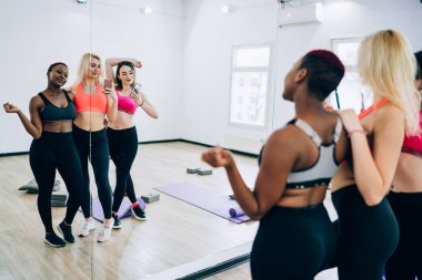 Spor sutyen ve tayt giyen çekici bir grup kadın fitness kulübünde çalıştıktan sonra ayna selfie 'si için poz veriyorlar.