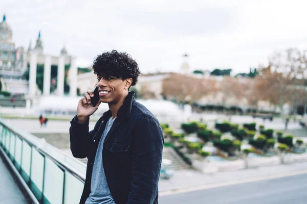 Latino male tourist using roaming internet for making online call via cellphone app for communicate about Spanish trip, cheerful hipster guy phoning with international connection for talking