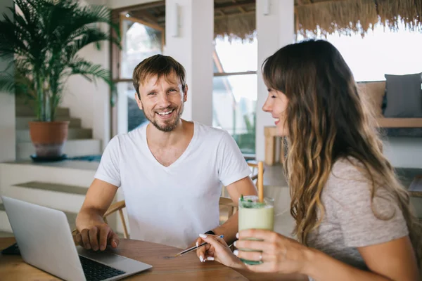 Smiling Millennial Freelancers Sitting Table Woman Refreshing Drink Reading Laptop — Stock Photo, Image