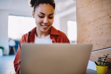 Yüzünde sevimli bir gülümseme olan koyu tenli kadın blogcu dizüstü bilgisayarda güncellenen yazılımla ilgili haberleri arıyor, içerik web siteleri hakkında bilgi okumak için internette gezinen mutlu hippi kız.