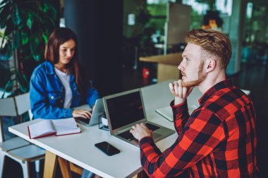 Hippi adamın düşünceli bakışlarını başka yöne çeviriyor ve bilgisayarla iletişim kurmak için yeni bir uygulama düşünüyor. Uzaktan kumandalı iş için zaman harcıyor. Önde oturan bayan meslektaşımla.