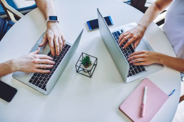 Birlikte çalışma alanında ücretsiz kablosuz internet kullanarak web sitesine içerik yüklemek için yazı yazan erkek ve kadının el yazısının kırpılmış görüntüsü, dizüstü bilgisayarlarda yazılım güncelleyen profesyoneller