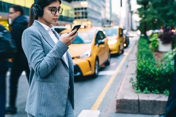 Przemyślana Kobieta Okularach Nosząca Ubrania Biurowe Przeglądająca Smartfony Zainteresowaniem Stojąc — Zdjęcie stockowe