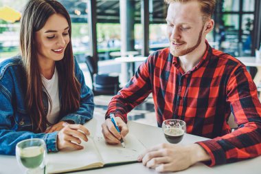 Kolej derslerini analiz eden pozitif erkek ve bayan öğrenciler kafeteryada boş zamanlarında temel ders kitaplarına ana tezi yazıyorlar, mutlu arkadaşlar birlikte defter içinde gezi planlıyorlar.
