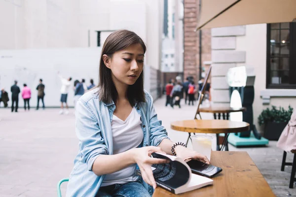 Brunett Asiatisk Kvinna Blå Skjorta Läsa Bok Och Använda Smartfoe — Stockfoto