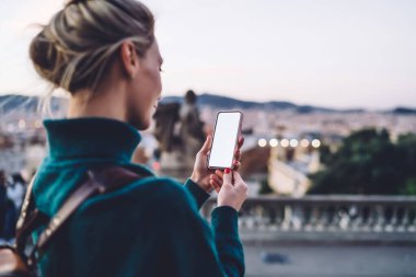 Tanımlanamayan, sarı saçlı, akıllı telefonlu ve bulanık arka planda boş ekrana bakan kadın turistin arka plan görüntüsü.