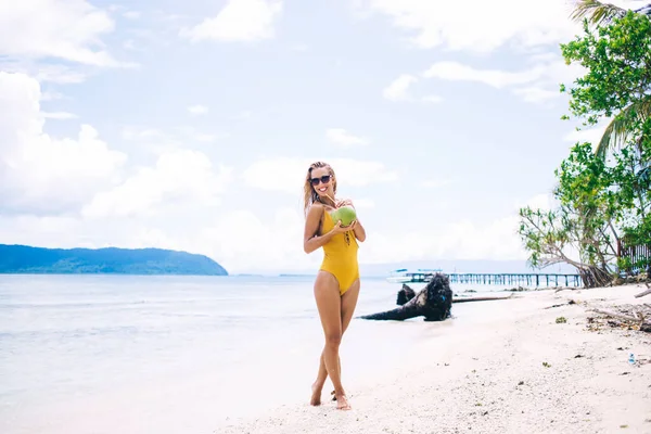Young Smiling Blonde Yellow Swimsuit Sunglasses Legs Crossed Standing Beach — ストック写真