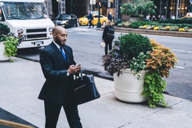 Mavi kravatlı, deri çantalı ve sokakta yürürken mesajlaşan kel, Afro-Amerikan iş adamlarından memnunum.  