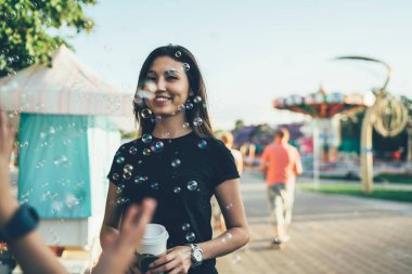 Millennial Asyalı turistin yarım boy portresi baloncukların yanında duruyor ve kendini lunaparktaki çocuk gibi hissediyor, neşeli hippi kız yaz tatillerinde dinlenmek için boş günlerini geçiriyor.