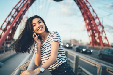 Gündelik giysiler içinde gülümseyen Y neslinin yarım boy portresi. Arkadaşınızı aramak ve seyahat detaylarını tartışmak için uluslararası internet bağlantısını kullanarak dolaşın.