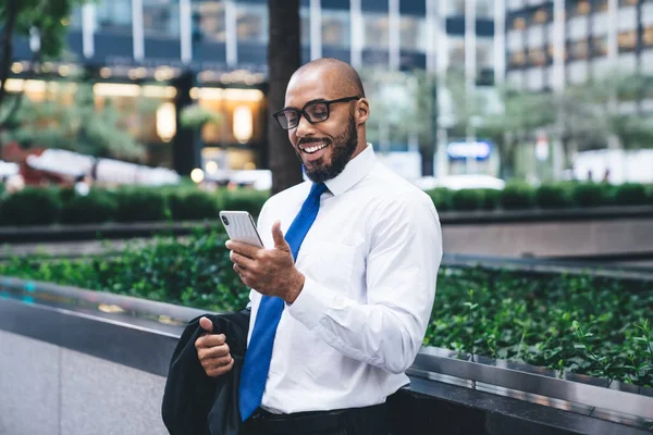 Щасливий Етнічний Чоловік Офісному Одязі Окулярах Тримає Піджак Використовує Смартфон — стокове фото