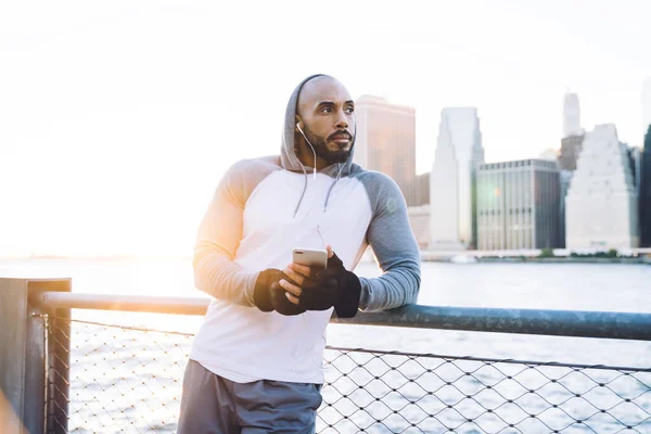 Thoughtful Ethnic Man Sportswear Headphones Listening Music While Standing City — Stock Photo, Image