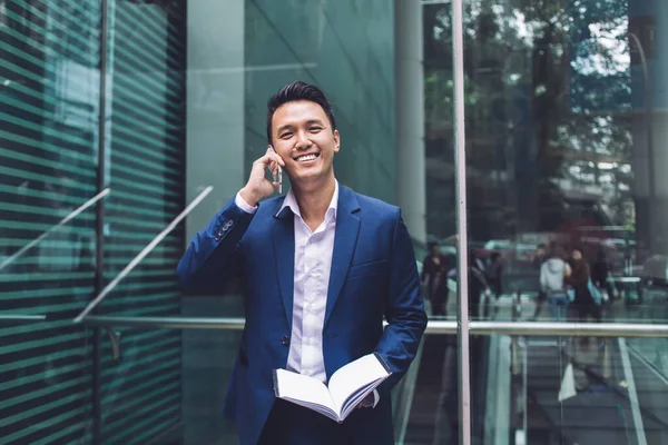 Sonriente Hombre Asiático Traje Hablando Teléfono Inteligente Sosteniendo Organizador Abierto —  Fotos de Stock