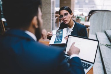 Sıkı siyah takım elbiseli konsantre iş arkadaşları laptopta sörf yaparken ve şehir merkezindeki kafede diyagramlar incelerken sohbet ediyorlar. 