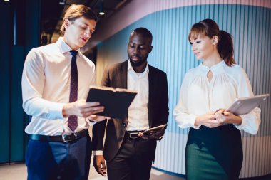 Çeşitli profesyonel gruplar, iş yerinde yürüyen ve şirket geliştirme fikirleri ile ilgili panosu olan erkek meslektaşlarını dinliyorlar.