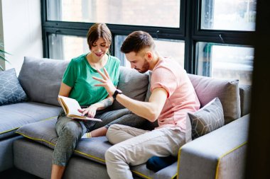 Birbirine aşık mutlu çift şık bir dairede rahat bir kanepede dinleniyor ve edebiyat kitabı okuyor, olumlu gülümseyen bir evlilik modern tasarım ile dairede en çok satan kitapların konusunu tartışıyor.
