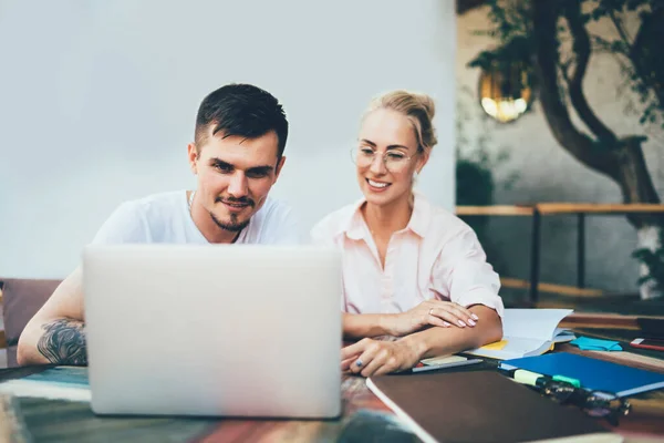 Content Man Woman Sitting Table Copybooks Looking Attentively Laptop Pointing — Stock Photo, Image