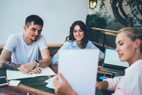 Bulanık bir bayan, terasta masada otururken ve serbest proje üzerinde çalışırken meslektaşlarına bilgilerle birlikte gülümsüyor ve kağıtları gösteriyor.