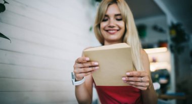 Mektuplar alıp modern kafede çalışırken elinde bir zarf tutan ve iyi haberler bekleyen neşeli genç bayandan.