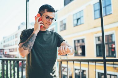 Beyaz çağdan kalma hippi adam arkadaşınla buluşmayı beklerken takılabilir akıllı saati kontrol ediyor ve detayları soruyor. Gözlüklü genç adam iletişim kurmak için dolaşım bağlantısını kullanıyor.