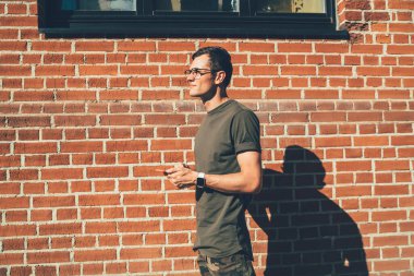 Elinde cep telefonu olan düşünceli genç adam oyuncular için web sitesinde metin incelemesi yapma fikri üzerine kafa yoruyor. Yaz şehrinde boş zamanlarında akıllı telefon aleti kullanan düşünceli hippi adam.