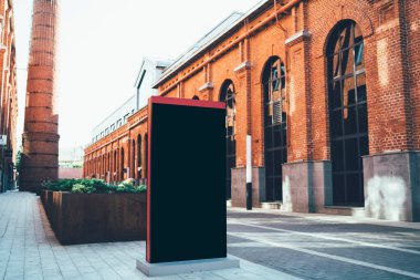 Boş siyah modern dikey reklam pankartı kentsel caddedeki kırmızı tuğla binanın yanında kırmızı çerçeveli.