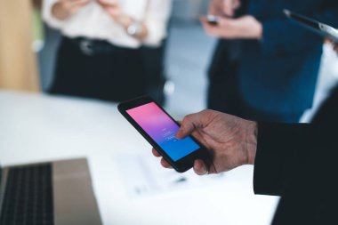Tanımlanamayan ofis çalışanının erkek eli bilgisayarın klavyesi ile bulanık arka plandaki akıllı telefon uygulaması ile şifreli kişisel bilgilerini giriyor.