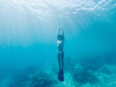 Genç bir turist, okyanus ekipmanlarını kullanarak tropik mercan resiflerinin yanında şnorkelle yüzüyor, yüzgeçli bir kadın, Raja Ampat 'ta gezinti tatili sırasında su altı derinliğini ve su yaşamını keşfediyor.