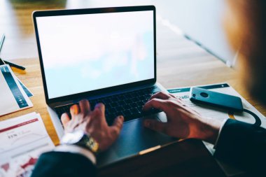 Ofisteki ahşap masada oturan ve akıllı telefon grafikleriyle ofiste çalışan tanınmayan bir işadamından. 