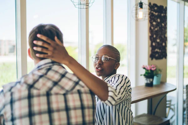 Chytrá Africká Američanka Brýlích Dotýkající Hlavy Mladého Muže Sedícího Stolu — Stock fotografie