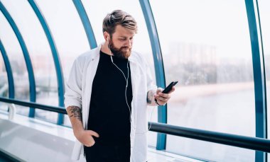 30 'lu yaşlardaki adam, elektronik kulaklıklardan çalma listesi kullanarak içeride durup müzik dinlerken iş arkadaşından gelen e-postayı kontrol ederken, hipster adam mesajları aldı ve oyuncu şarkısını seçti.