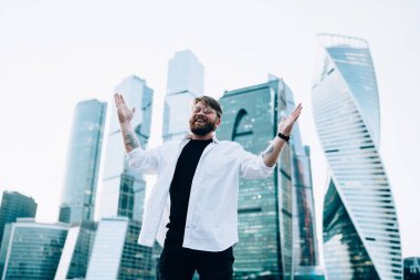 Moda optik gözlüklü neşeli beyaz erkek portresi kameraya gülümseyen ve mutlu hippi adam sevinçten havalara uçarken ellerini kaldıran gözler için koruma sağlıyor.