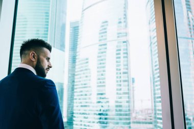 Resmi olarak başarılı bir yönetici pencereden dışarı bakıyor ve gündüz vakti aydınlık ofis binasında tek başına dikilirken düşünüyor.