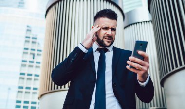 Modern şehrin merkezinde caddede dikilirken, takım elbiseli, kaşlarını çatan ve akıllı telefonları karıştıran...