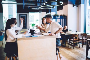 Canlı, çoklu etnik çeşitlilikteki iş adamlarının modern bürodaki belgelerle masada otururken konuşma ve el kol hareketleri yapmaları. 
