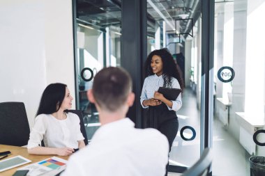 Dosyasıyla gülümseyen siyah kıvırcık kadın, yeni başlayanlar şirketine modern konferans odasındaki iş için geliyor.
