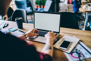 Yukarıdan gelen isimsiz bir erkek dizüstü bilgisayarı izliyor. Elinde bir fincan kahve fincanı ve yaratıcı çalışma alanında kahve bardağı şeması var.