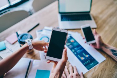 İş arkadaşlarının üst katlarından, günlük kıyafetlerini giyip masada oturmuş iş yerindeki kahve diyagramlarıyla cep telefonlarını izliyorlar.